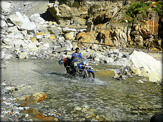 cossing a rocky river bed on a motorcycle in india